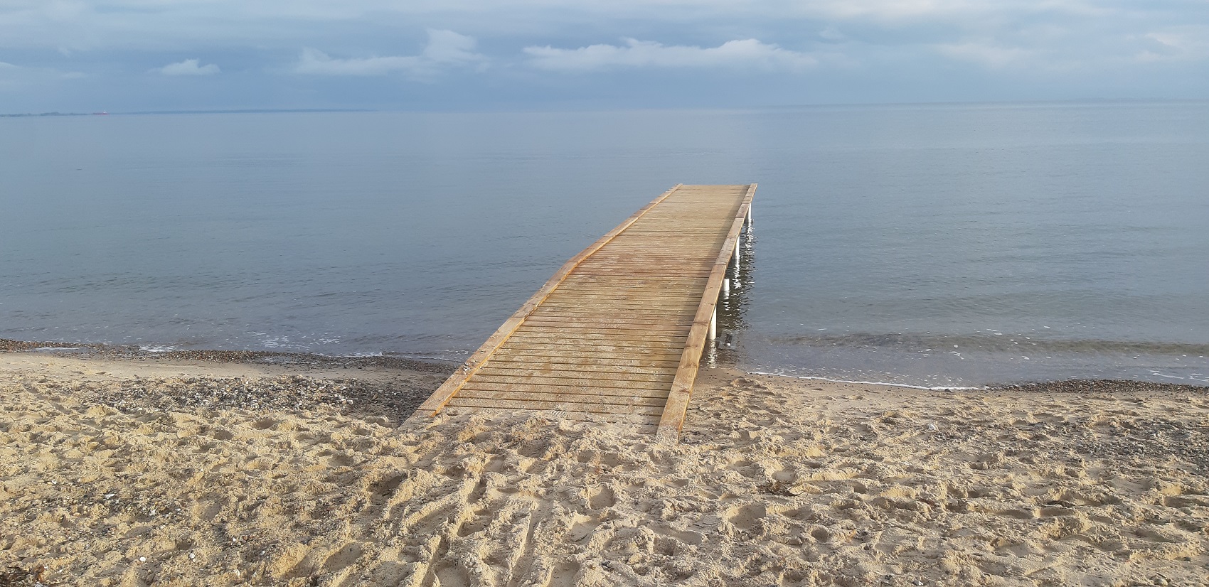 Badebroen i Juelsminde set fra stranden i stille vejr